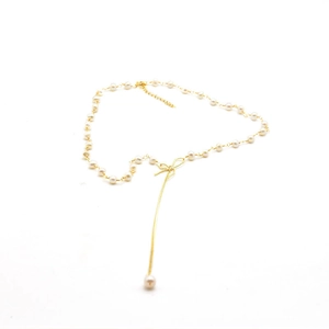 Elegant natural freshwater pearl necklace with gold bow pendant and dangling tassels