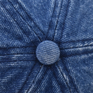 Dettaglio ravvicinato del bottone superiore e delle cuciture del cappello denim