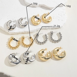 Set of gold and silver C-shaped chunky brass hoop earrings on white stone background
