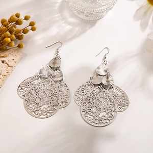 Gros plan de boucles d'oreilles feuilles évidées argentées au motif floral d'eau