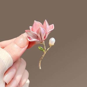 Macro detail of magnolia flower brooch with pink enamel petals and a round pearl