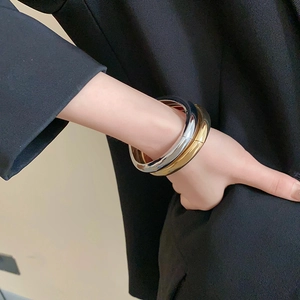 Close-up of chunky gold and silver plated bangles with a polished mirror finish on model