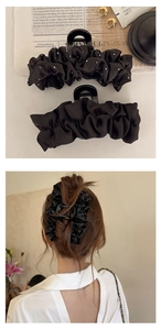 Détail de grandes pinces à cheveux en satin noir plissé montrant la texture et l'usage