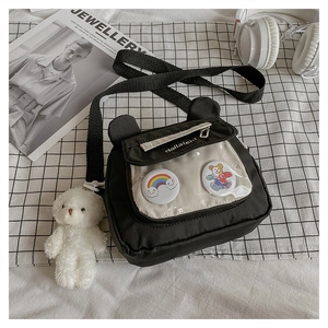 Black canvas shoulder bag with cute bear charm and colorful pins on checkered background