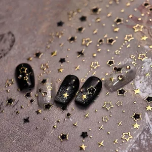 Macro shot of gold and black star nail stickers on dark and glittery manicured nails