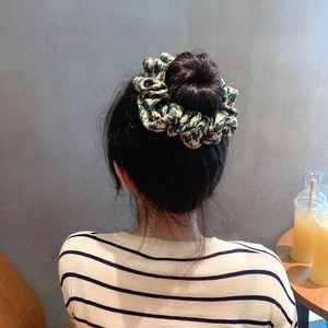 Green and white houndstooth cotton scrunchie hair tie worn on a stylish hair bun