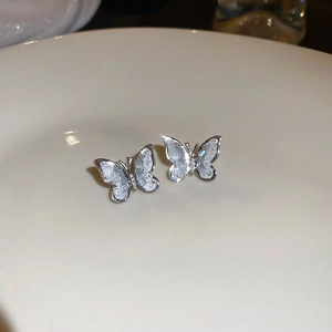 Detailed close-up of butterfly stud earrings with ice-textured crystals on white ceramic