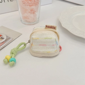 Detail of tweed earphone pouch with gold zipper and colorful beaded tassel keychain
