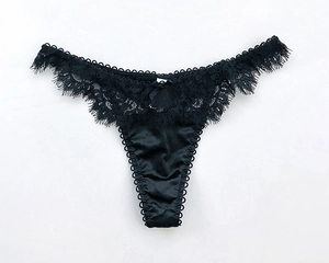 Dettaglio del perizoma in pizzo nero con un fiocco di seta sulla vita elastica