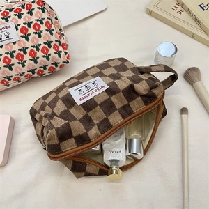 Detailed view of checkered corduroy toiletry bag with top handle and smooth zipper