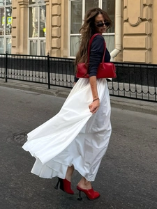 Detail of white maxi skirt styled with red leather handbag and matching pointed mules