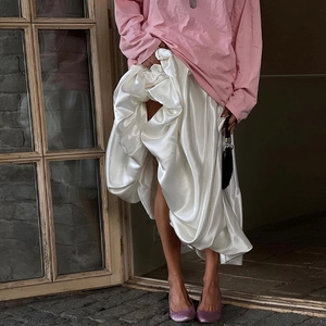 Detail of white satin midi skirt showing smooth glossy texture and elegant drape effect
