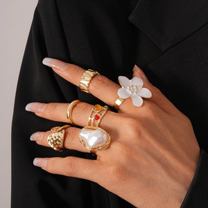 Détail d'un lot de six bagues dorées avec motifs floraux et perles sur un mannequin