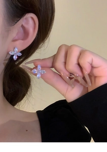 Close-up of sparkling silver zircon flower stud earrings with a four-petal star design