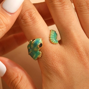 Detailed shot of a green enamel frog and caterpillar gold open ring on a finger