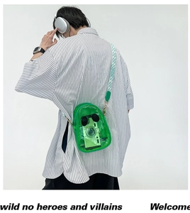 Model wearing a green transparent PVC crossbody jelly bag over a striped shirt