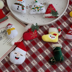 Assorted mini Christmas plush charms including Santa and snowman on festive tablecloth