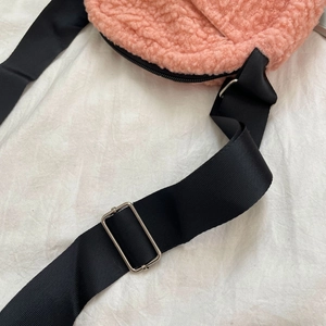 Detail of pink faux shearling crossbody bag with adjustable black wide nylon strap