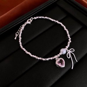 Detail of silver beaded necklace with pink heart zircon, bow charm, and white pearl