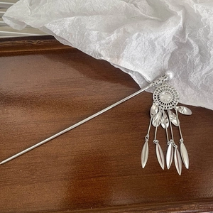 Detail view of silver hair pin with hollow pattern, pearl, and long tassel pendants