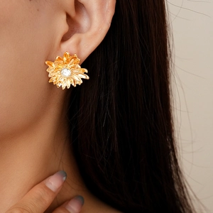 Macro view of gold daisy earrings with crystal center worn by a model in detail