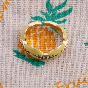 Detail of adjustable gold ring with light yellow enamel coating and dark zircon inlay