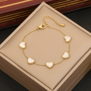 Bracelet doré avec pendentifs en nacre blanche en forme de cœur sur boîte à bijoux