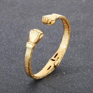 Dettaglio del bracciale a polsino con pugni da boxe dorati e texture martellata vintage
