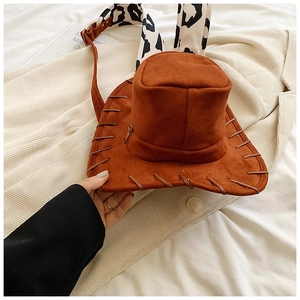 Close-up of brown cowboy hat backpack with cow print strap on corduroy fabric