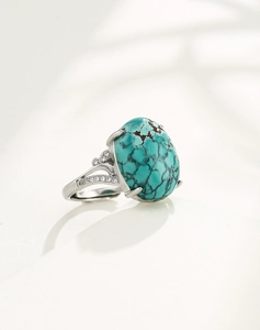 Macro view of oval turquoise ring with silver band and sparkling cubic zirconia accents