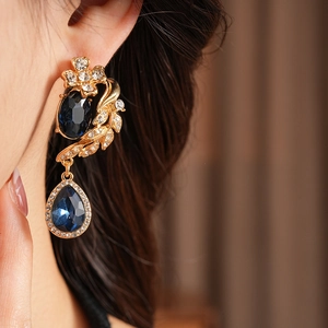 Gros plan de boucles d'oreilles vintage avec pierres bleues portées sous lumière chaude