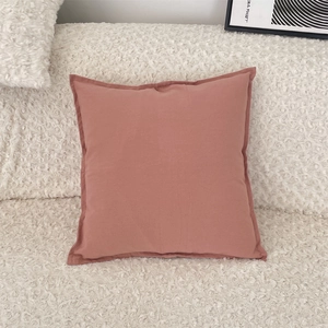 Close-up of minimalist dusty pink cushion cover with stitched edges on a white sofa