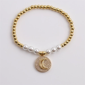 Gold plated bead bracelet with white pearl and sparkling zircon moon pendant on white background