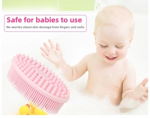 Pink silicone baby bath brush with soft bristles and massage nubs in a soapy bathtub