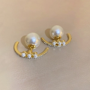 Detailed view of champagne gold pearl stud earrings with zircon accents on satin fabric