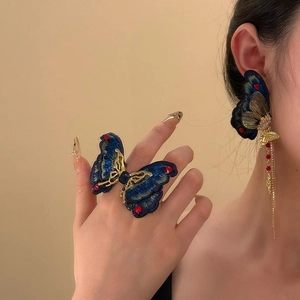 Close-up of vintage embroidered butterfly jewelry set with blue wings and gold tassels