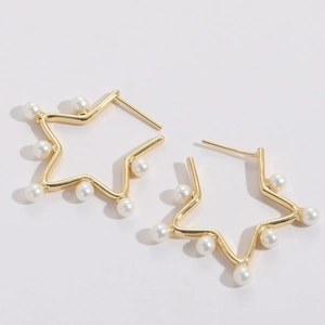 Detail of star-shaped gold-plated earrings with white pearls on a clean white background