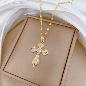 Detail of a gold cross pendant necklace with sparkling crystals on beige jewelry box