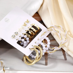 9-piece gold butterfly and pearl earring set on display card with stylish magazine backdrop