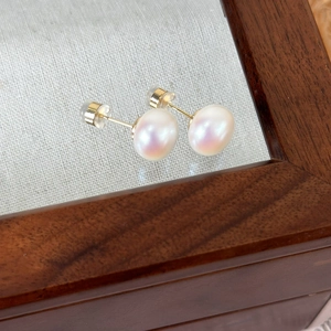 Macro shot of 9mm freshwater pearl earrings with pink luster and gold silicone backings