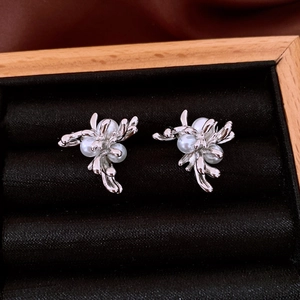 Detail shot of silver floral branch earrings with white pearls on black jewelry cushion