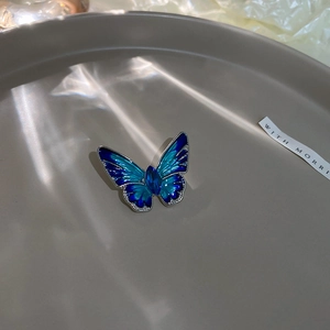 Macro detail of blue gradient enamel butterfly brooch with inlaid rhinestones