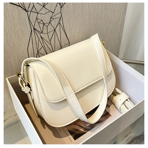 White leather shoulder bag with gold hardware and flap closure in a gift box