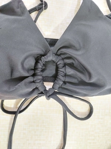 Detail of black bikini top with center ring connector and ruched fabric texture
