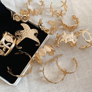 Detailed close-up of gold starfish and seashell bracelets on black velvet lining
