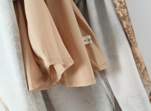 Macro shot of double-layer dress detail showing floral print fabric and beige lining