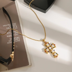 Dettaglio della collana con croce dorata con perle bianche e gemme su sfondo artistico curato