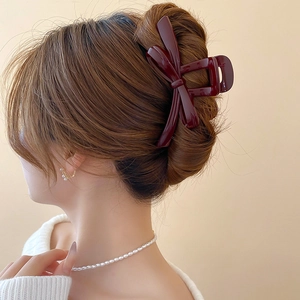 Detail showing elegant deep red bow hair claw clip styled in a refined updo bun