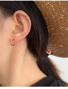 Close-up of elegant gold S925 sterling silver hoop earrings worn on a model's ear