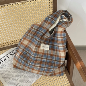 Detailed close-up of retro plaid canvas tote bag fabric and branded canvas patch